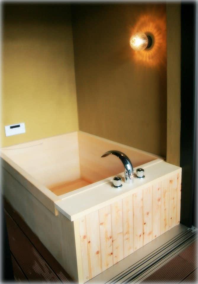Togakushi Shrine Shukubo Former Enmei-in Oyado Suwa Compact square wooden bathtub with metal faucet beneath a round wall light and pale textured walls