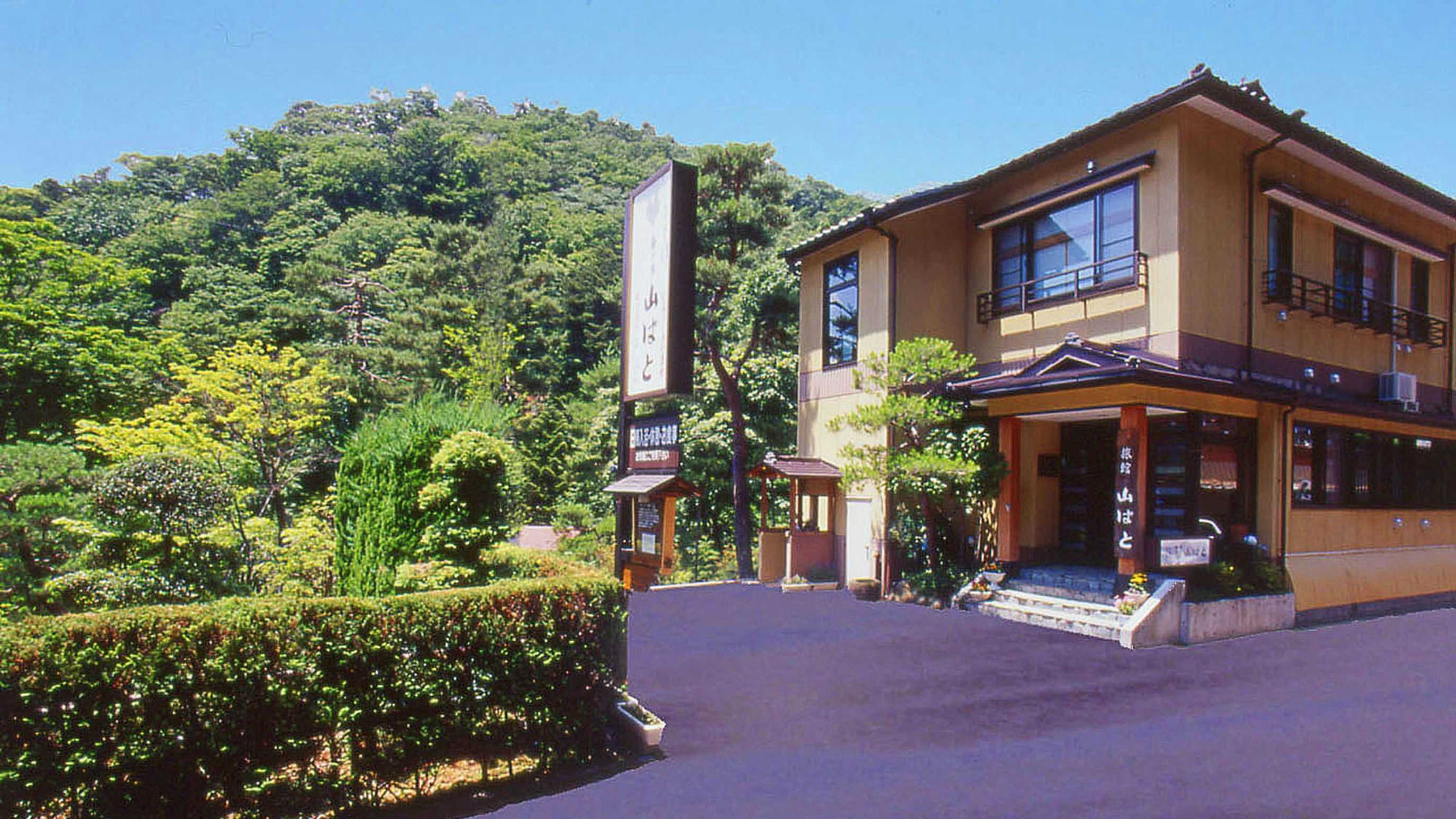 Yunoyado Yamabato lodging exterior and roadside sign beneath a blue sky