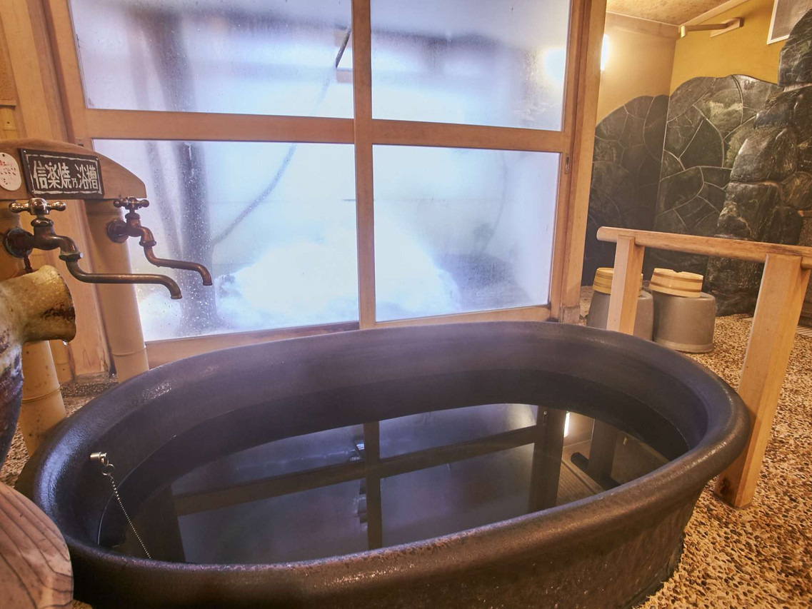 A round wooden soaking tub beside a window.