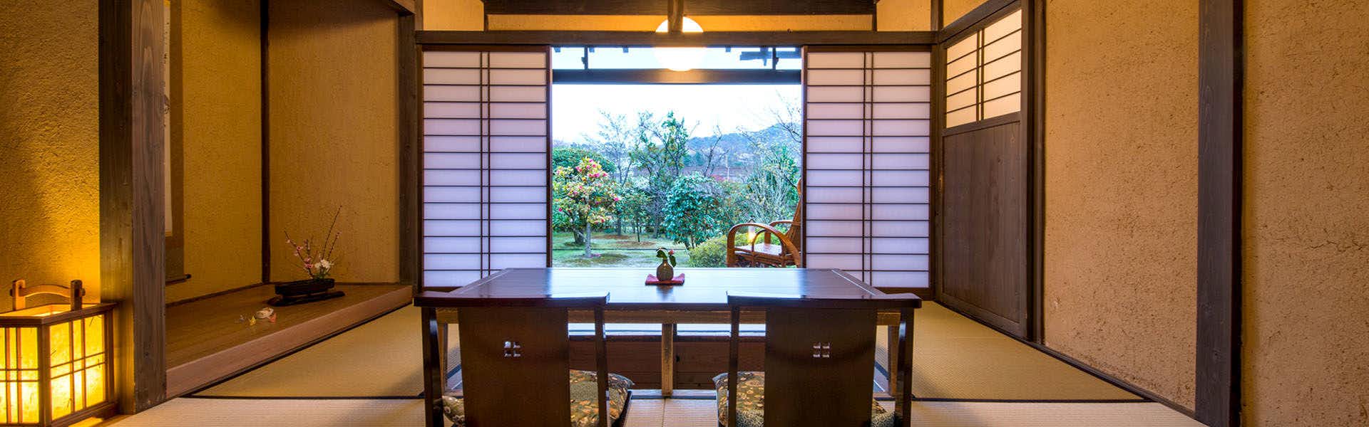 Hanare no Yado Waraku Interior with dark wood framing and horizontal slatted screens framing distant landscape of trees and mountains.