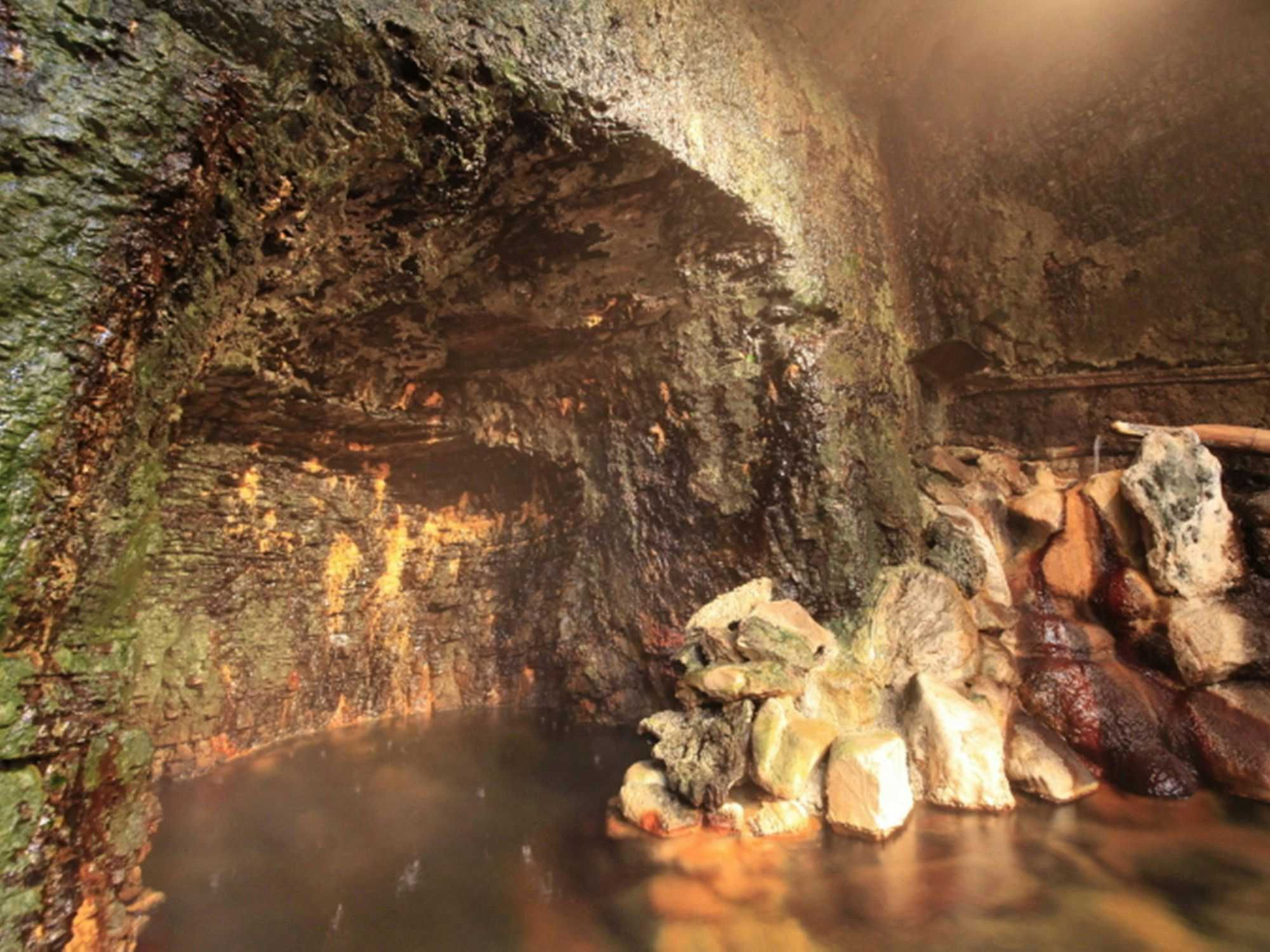 Genbi no Yado Aizuya with a steaming cave bath surrounded by rough natural rock.