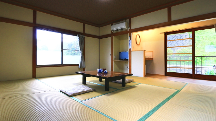 A spacious tatami room with a low table and windows facing greenery.