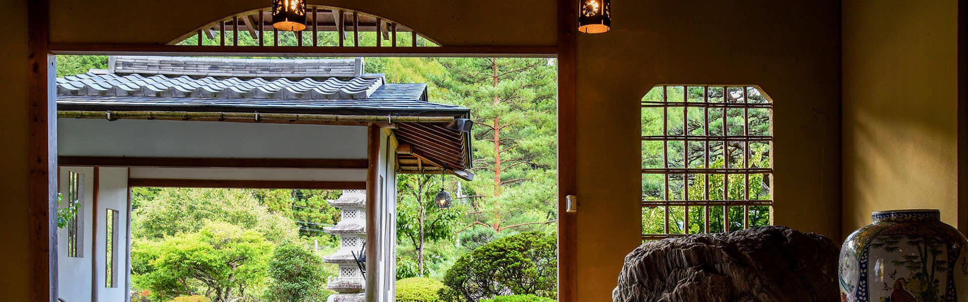 Irori Kaiseki and Juhyo Inn Fudo Onsen Hanabishi with a stone entrance corridor opening toward a green garden.