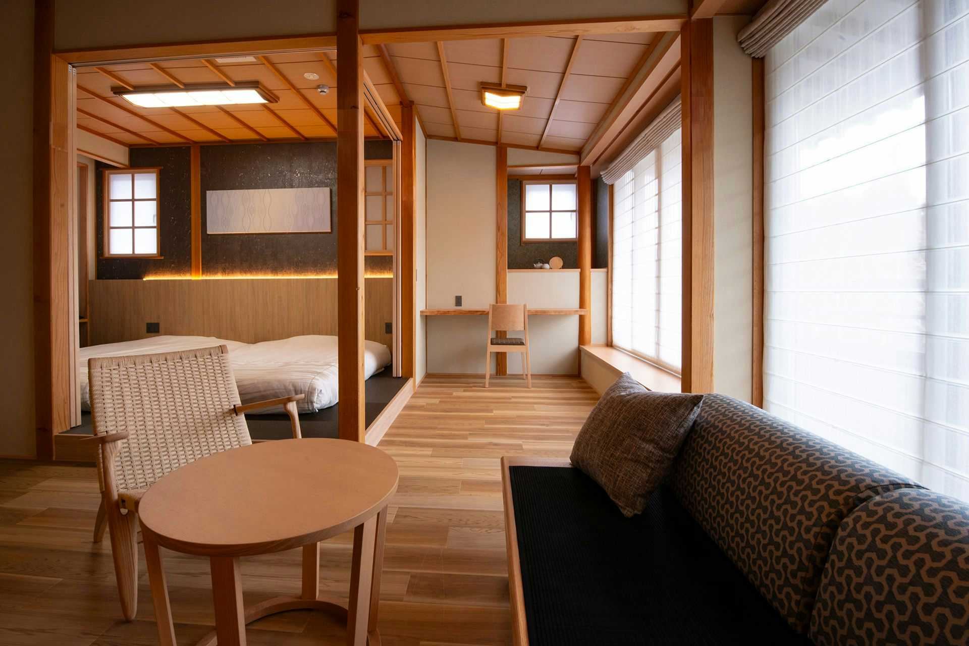 Matsurube Onsen Kamikura contemporary guest room with a sofa, round table and bed in an alcove