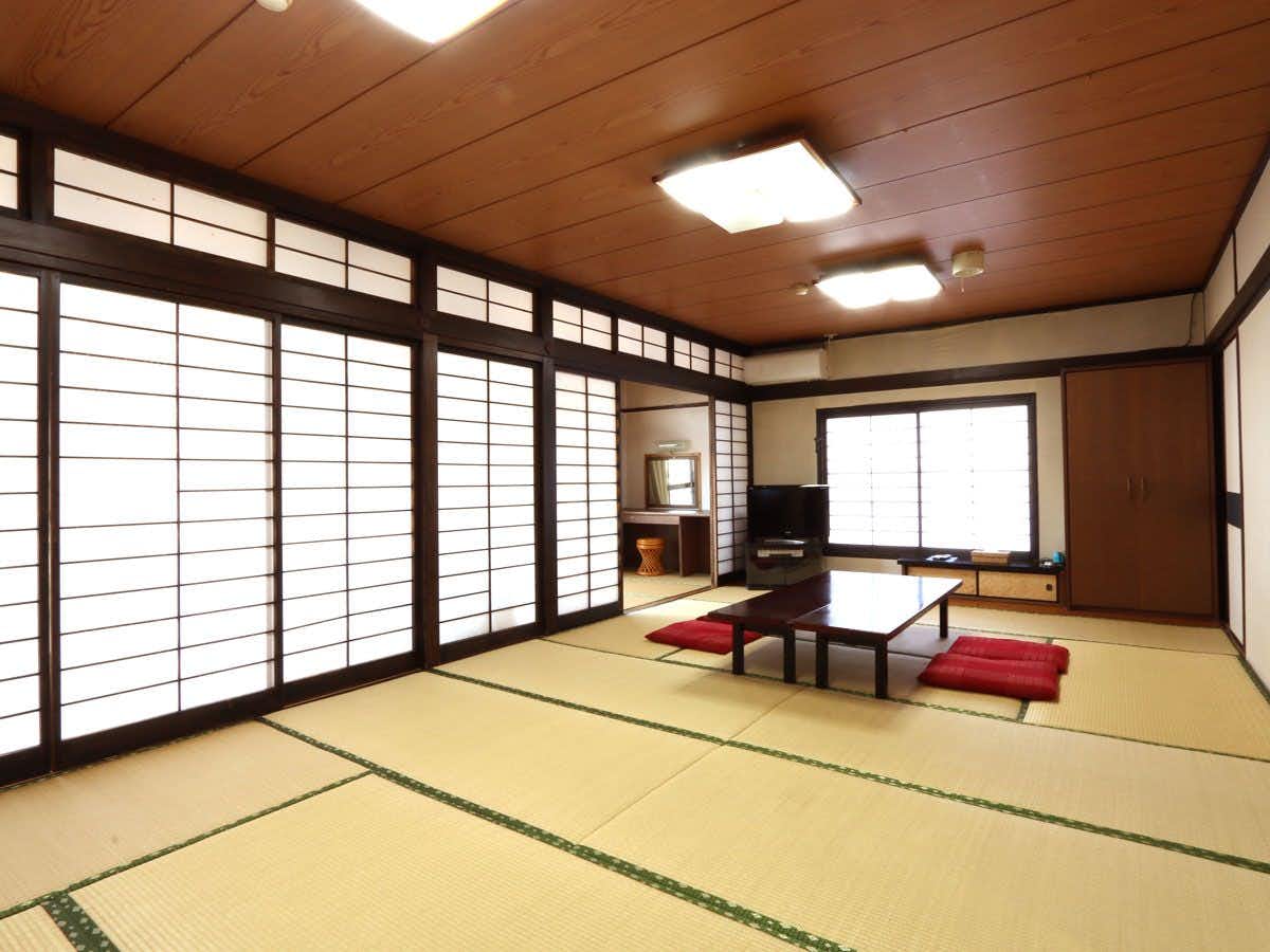 The Origin of Ueki Onsen - Ryokan Matsunoyu with a spacious tatami room with red cushions and low table.