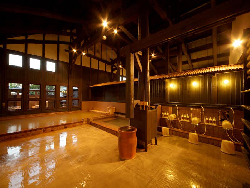 Katsuragi Onsen Happu no Yu "Yado Happu Bekkan" with an indoor bath glowing beside broad darkened windows.