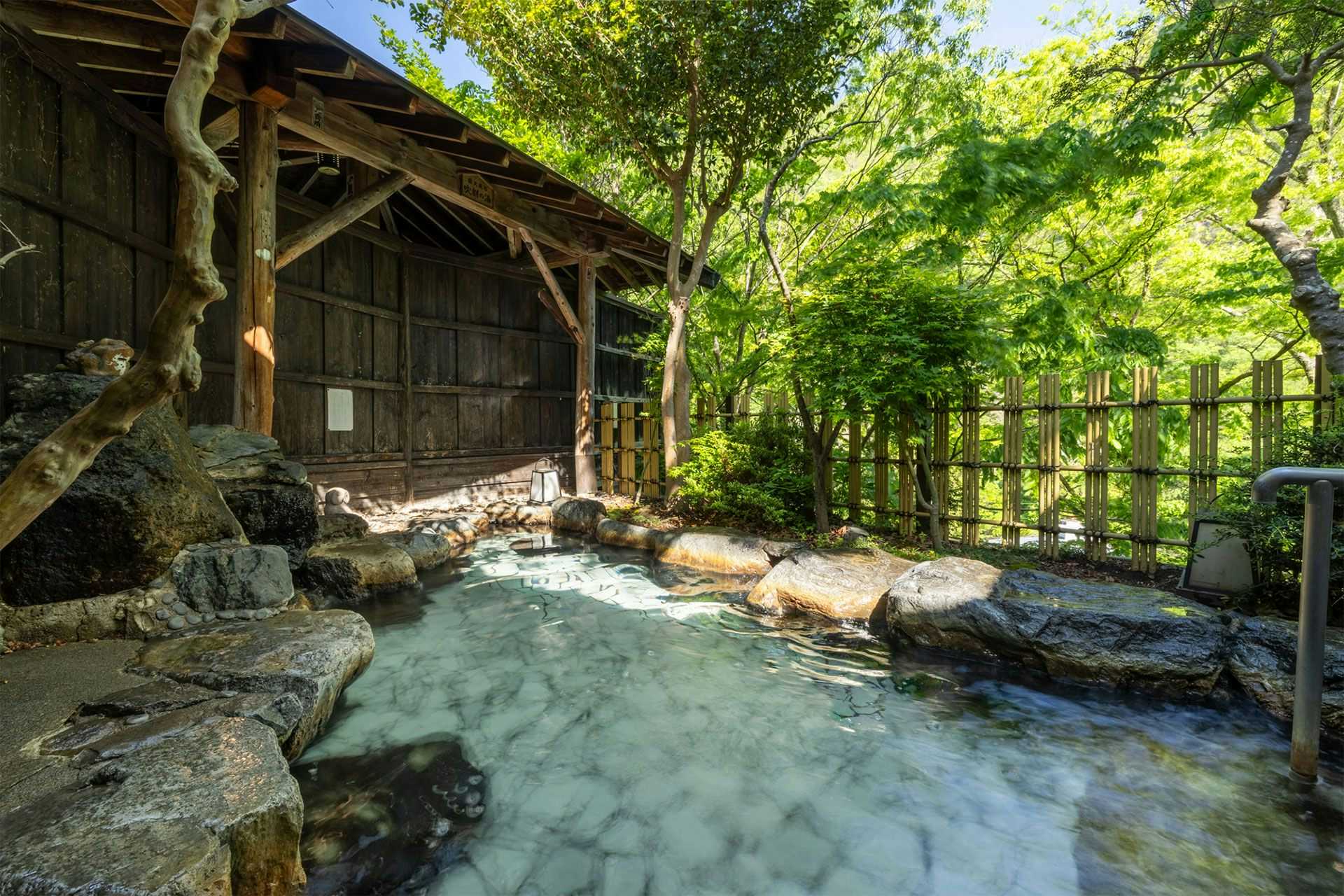 Ginshotei Awashima with an open-air rock bath surrounded by dense forest greenery.