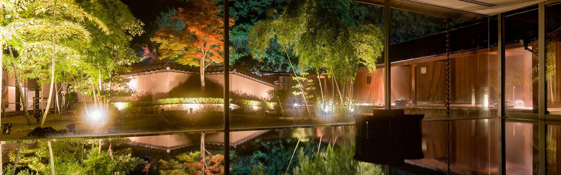 Hagi Honjin with an illuminated garden reflected across still water at night.