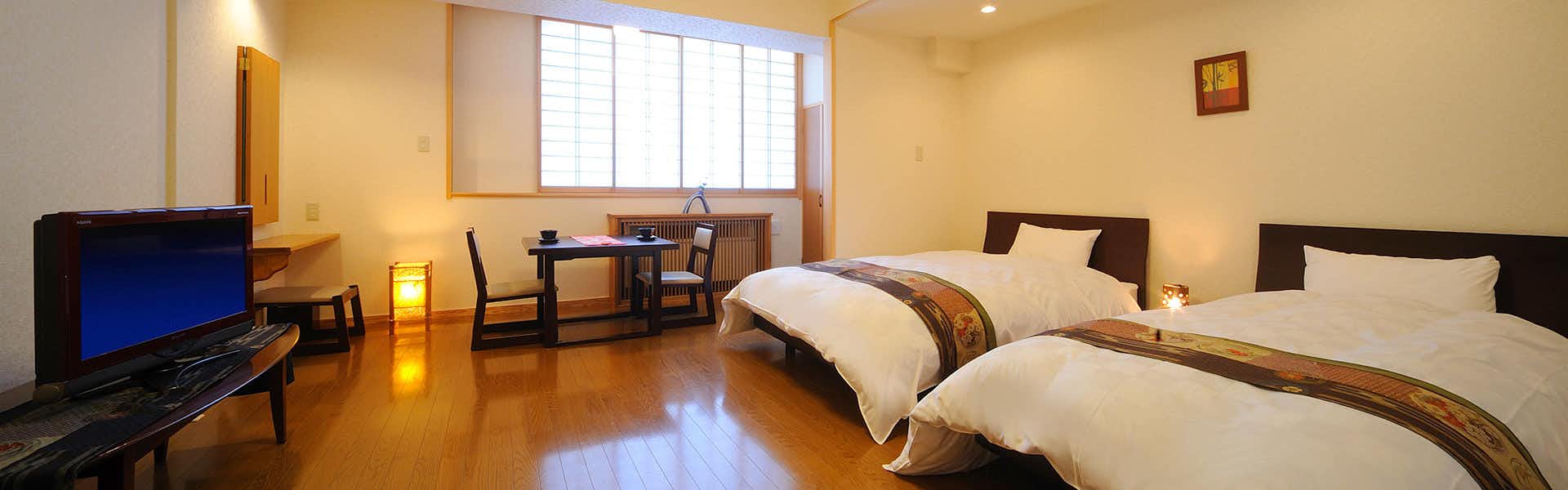 Kamasaki Onsen Suzukiya Ryokan with a modern twin bedroom adjoining a compact seating area.