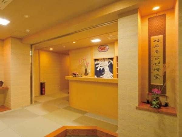 Ryokan Hamayuu Matsuiseki-an Warm reception lobby with pale counter, hanging scroll, flower arrangement, and softly lit tiled floor