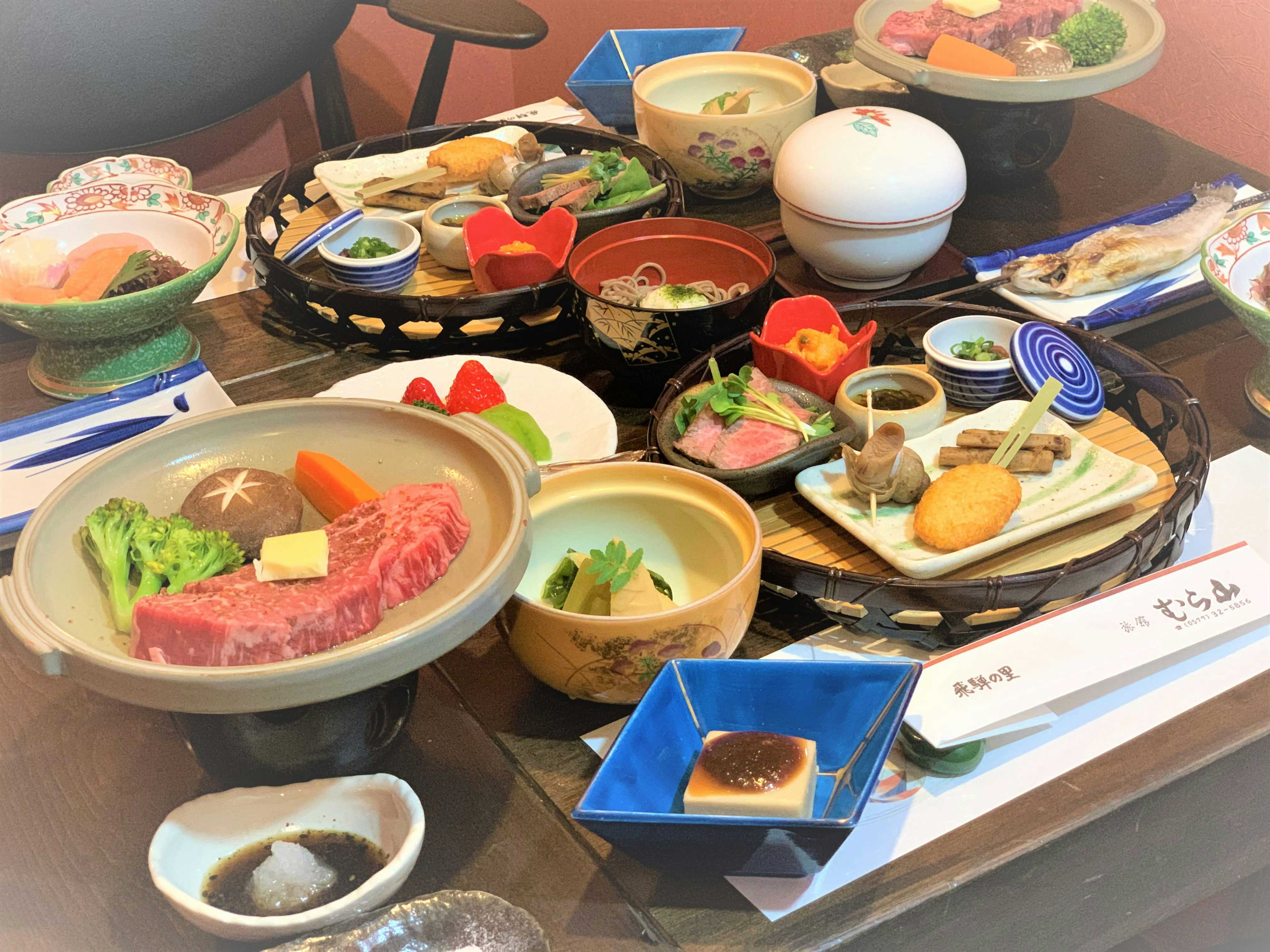 Ryokan Murayama with a generous Japanese dinner arranged across colorful ceramic dishes.