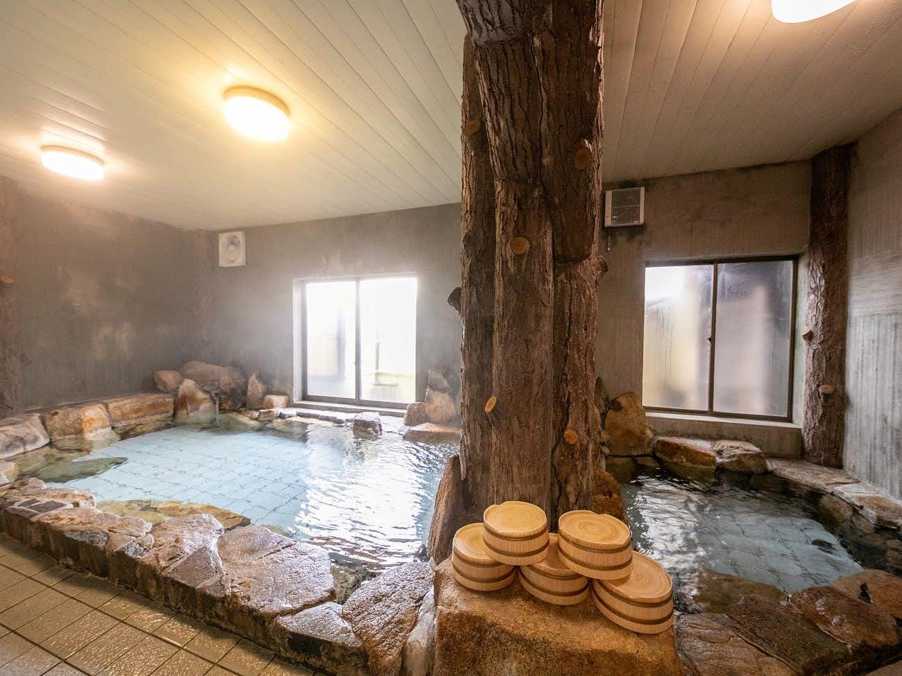 Chikuen Ryokan with an indoor rock bath built around a natural timber column.