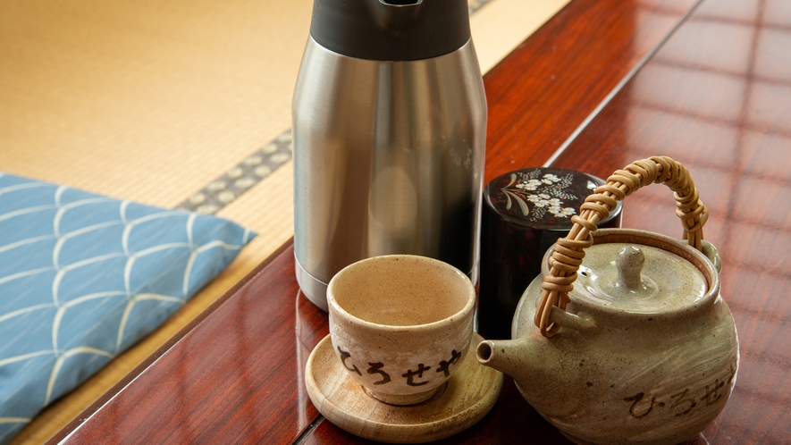 A teapot, cup, and insulated flask arranged on a low table.