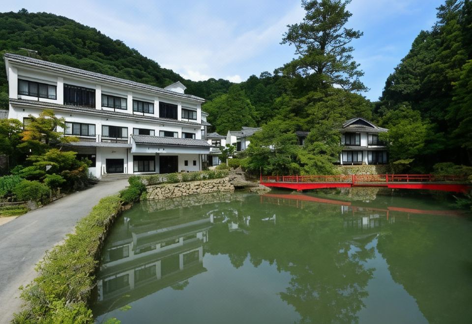 A ryokan beside a pond and red footbridge.
