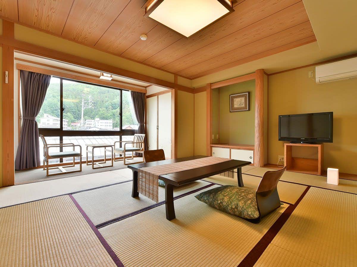 Nozawa Onsen Asahiya Ryokan with a traditional tatami room with low table and mountain view.
