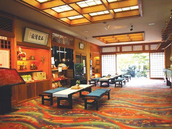 Izu Nagaoka Onsen Koubou no Yu Ikona-so with a colorful lobby with low tables and red carpeting.