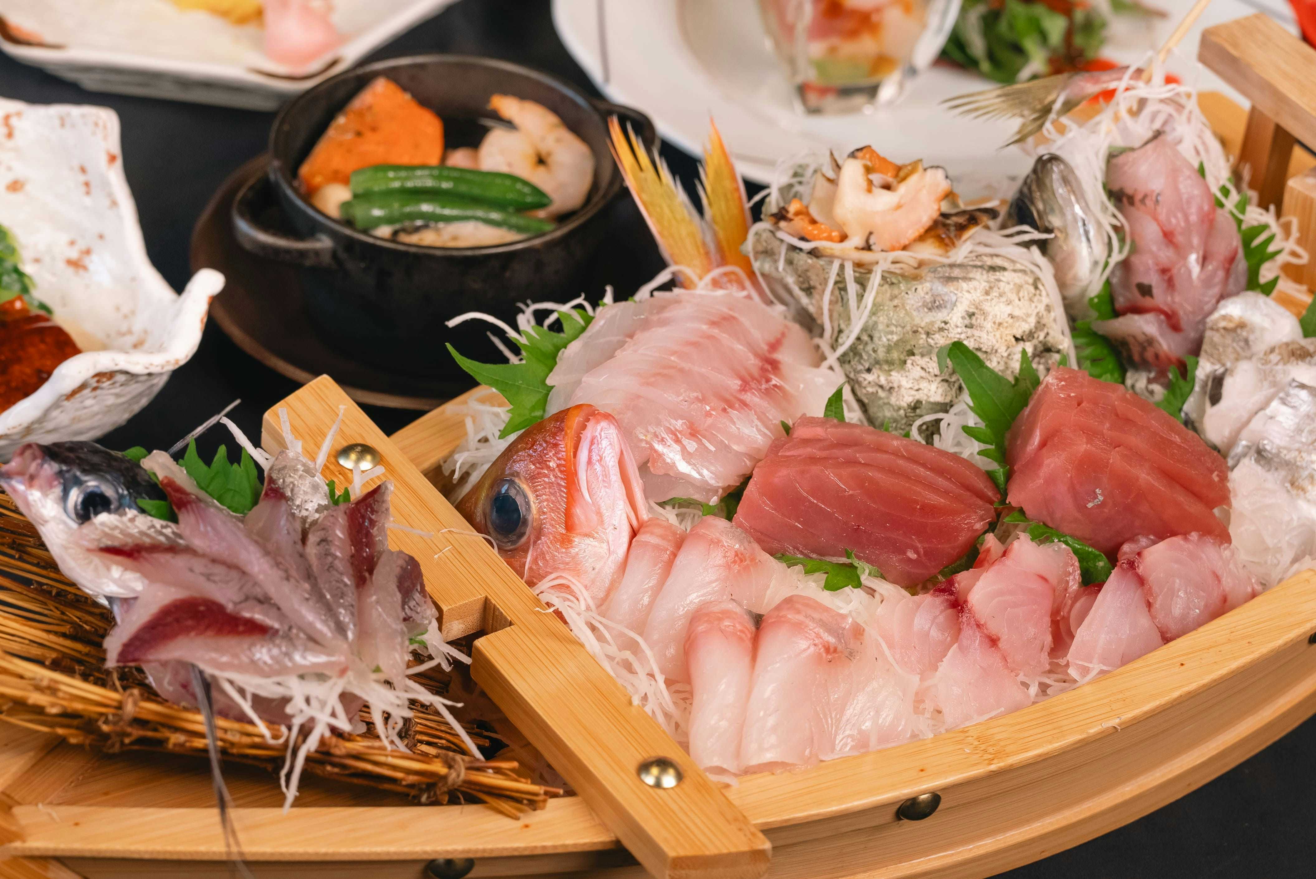 Oyado Uoki with a sashimi boat filled with tuna, shrimp, and silver fish.