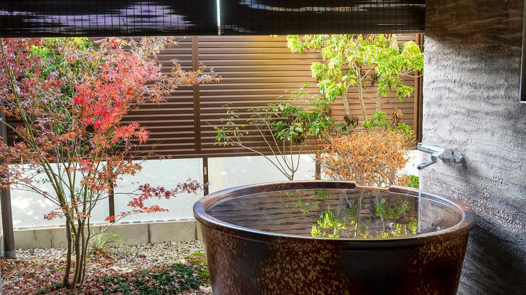 Yamaga Onsen Ryokan Miki with a round outdoor soaking tub beside red maple leaves.