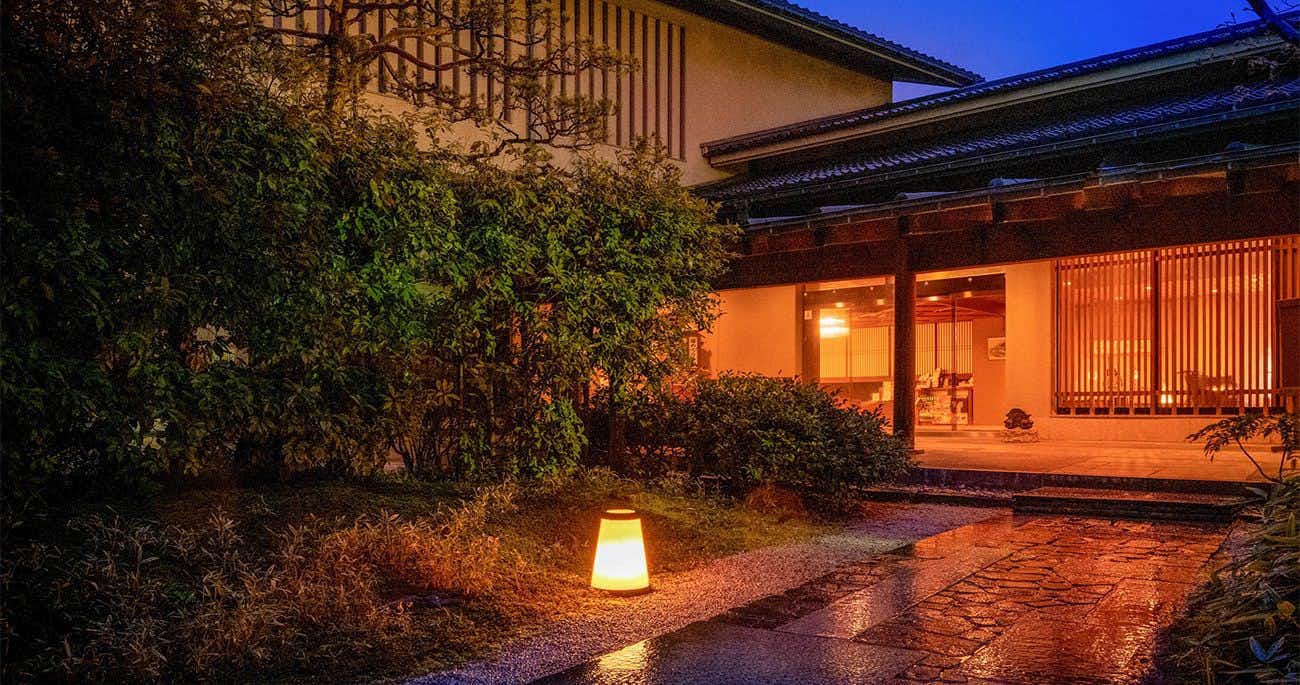 The timber entrance glowing beside a rain-darkened garden path.