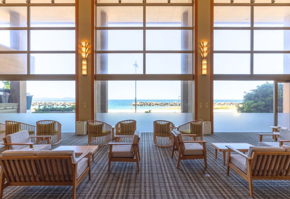 A bright dining area looks across the sea through tall windows.