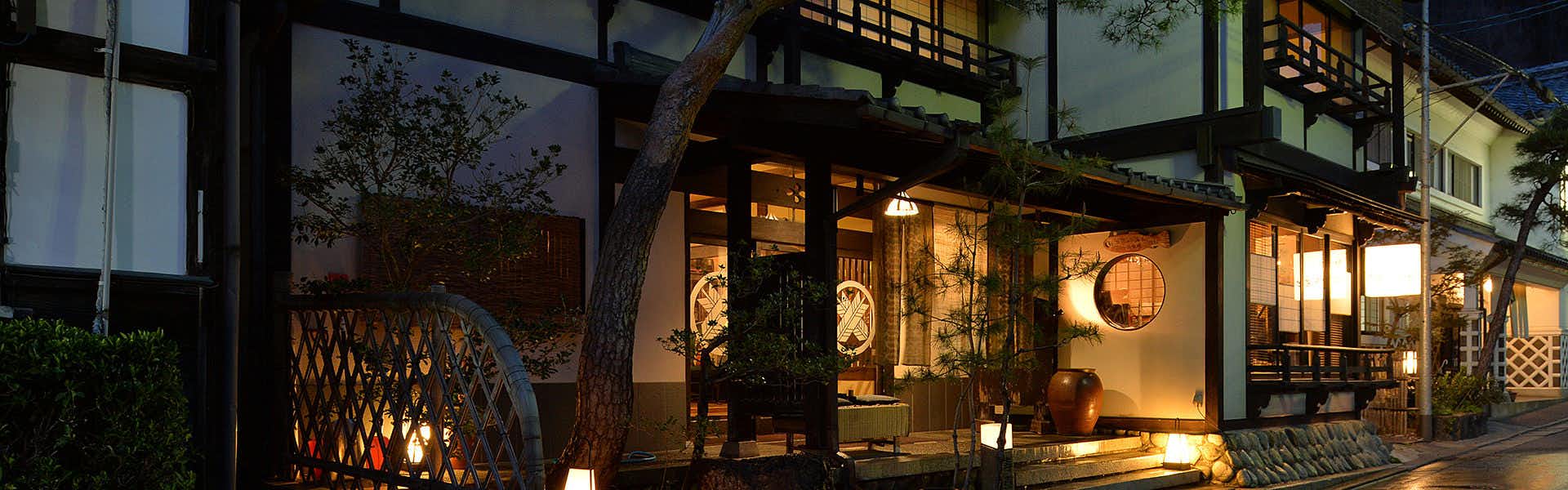 Ryokan Sugimoto lantern-lit lodging entrance with a circular window and garden trees