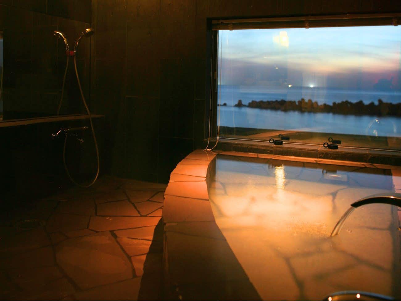 Annex Oyado Uotake with a private indoor bath reflecting the orange coastal sunset.