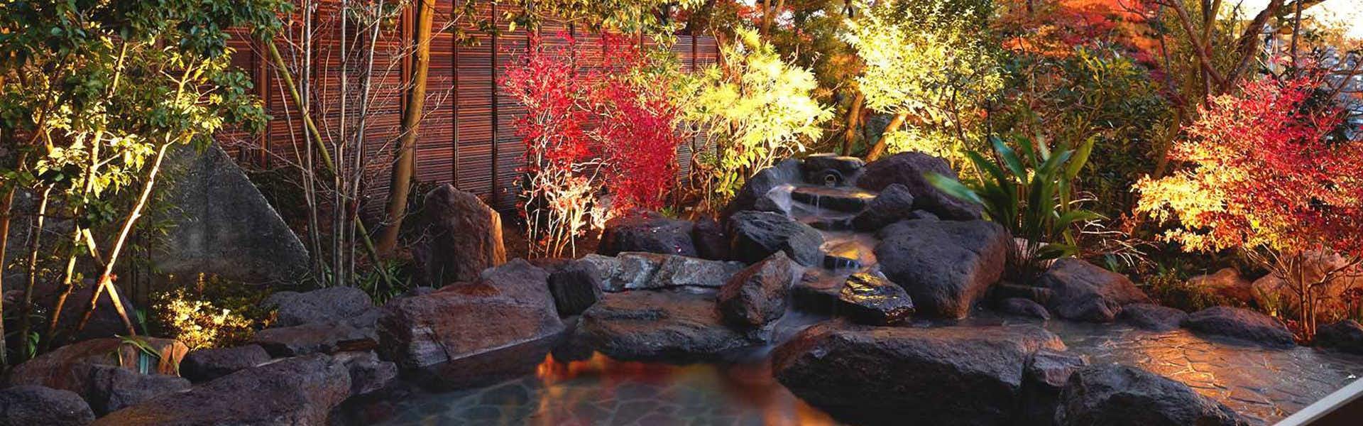 Motoyu Jinya Garden landscape with water feature, boulders, and foliage in warm red and orange tones