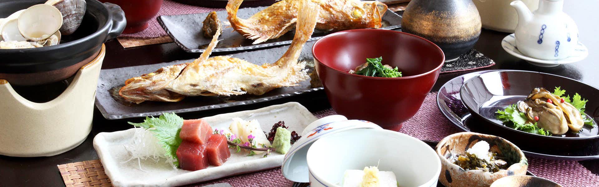 Tomoya Hotel with a traditional dinner arranged around grilled fish and sashimi.