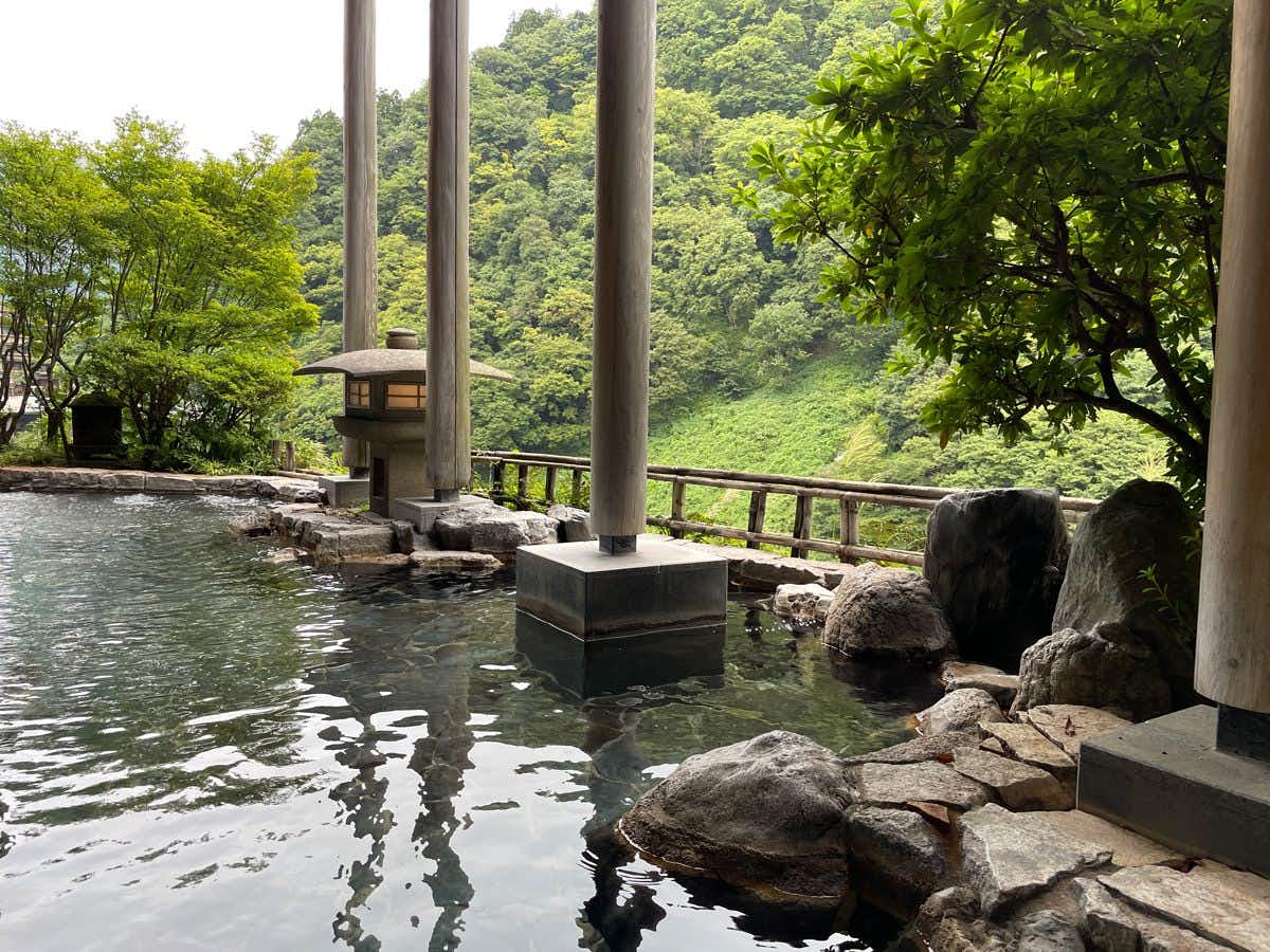 Entaiji-so with an outdoor stone bath overlooking dense green mountain forest.