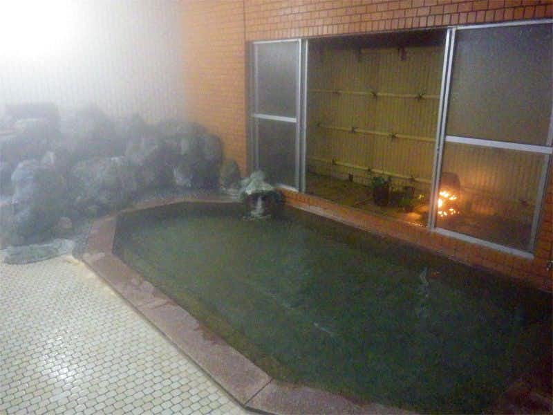 Oishiya Ryokan with an indoor mineral bath bordered by small mosaic tiles.