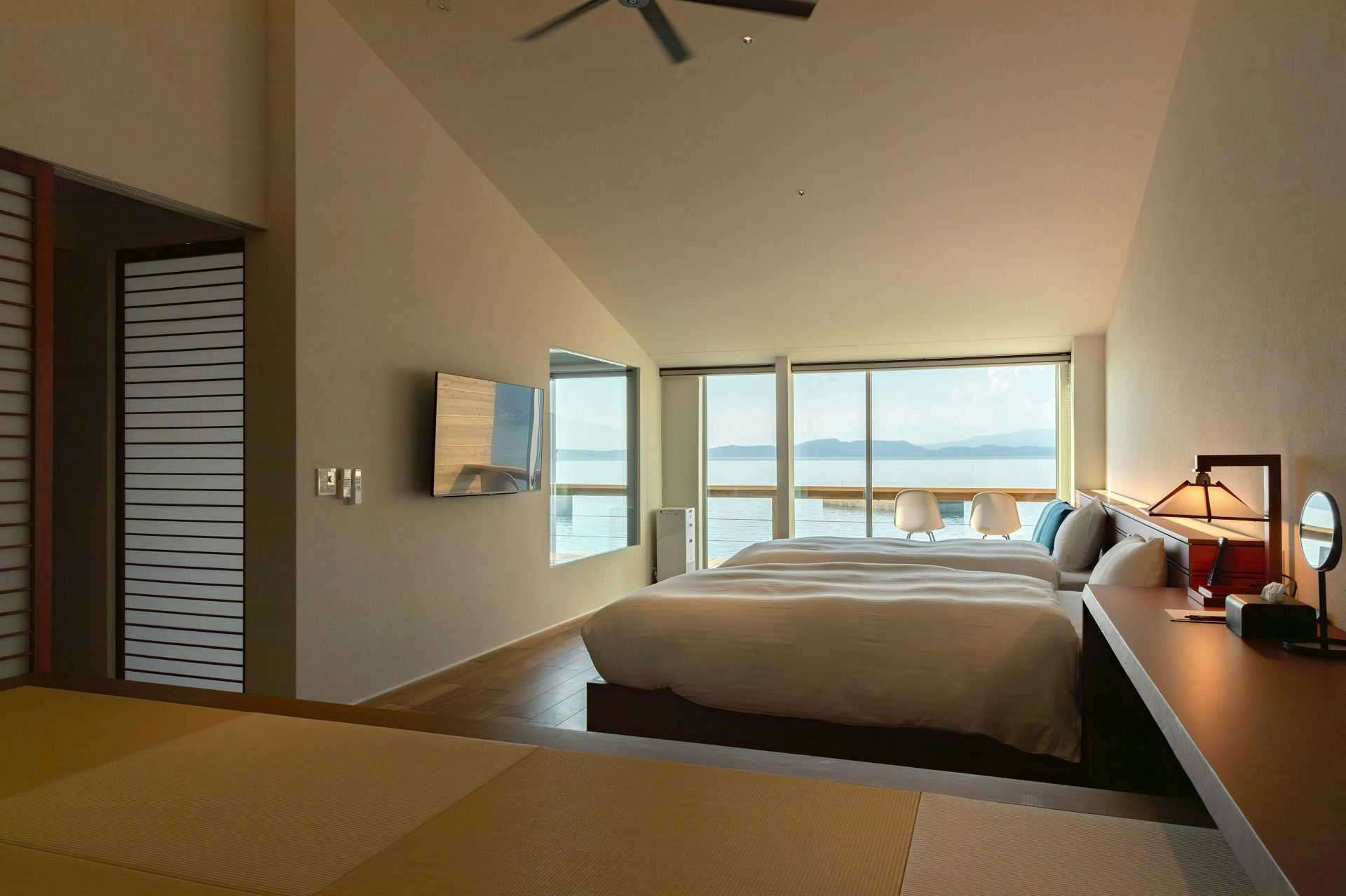 Obama Onsen Iseya with this scene, where a low bed and tatami seating face the sea through broad corner windows.