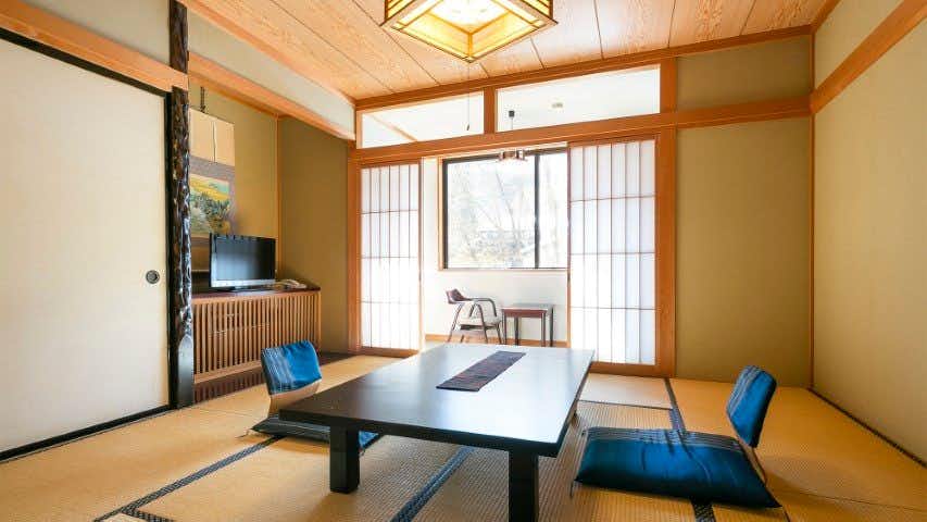 Onyado Hisui with this scene, where a bright tatami room places blue floor chairs around a low dark table.