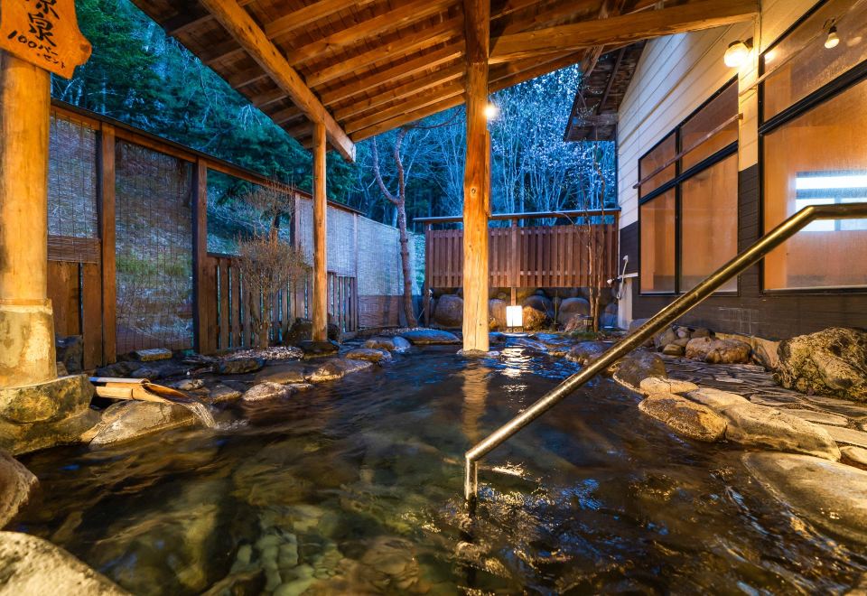 A covered rock-lined bath with a handrail.