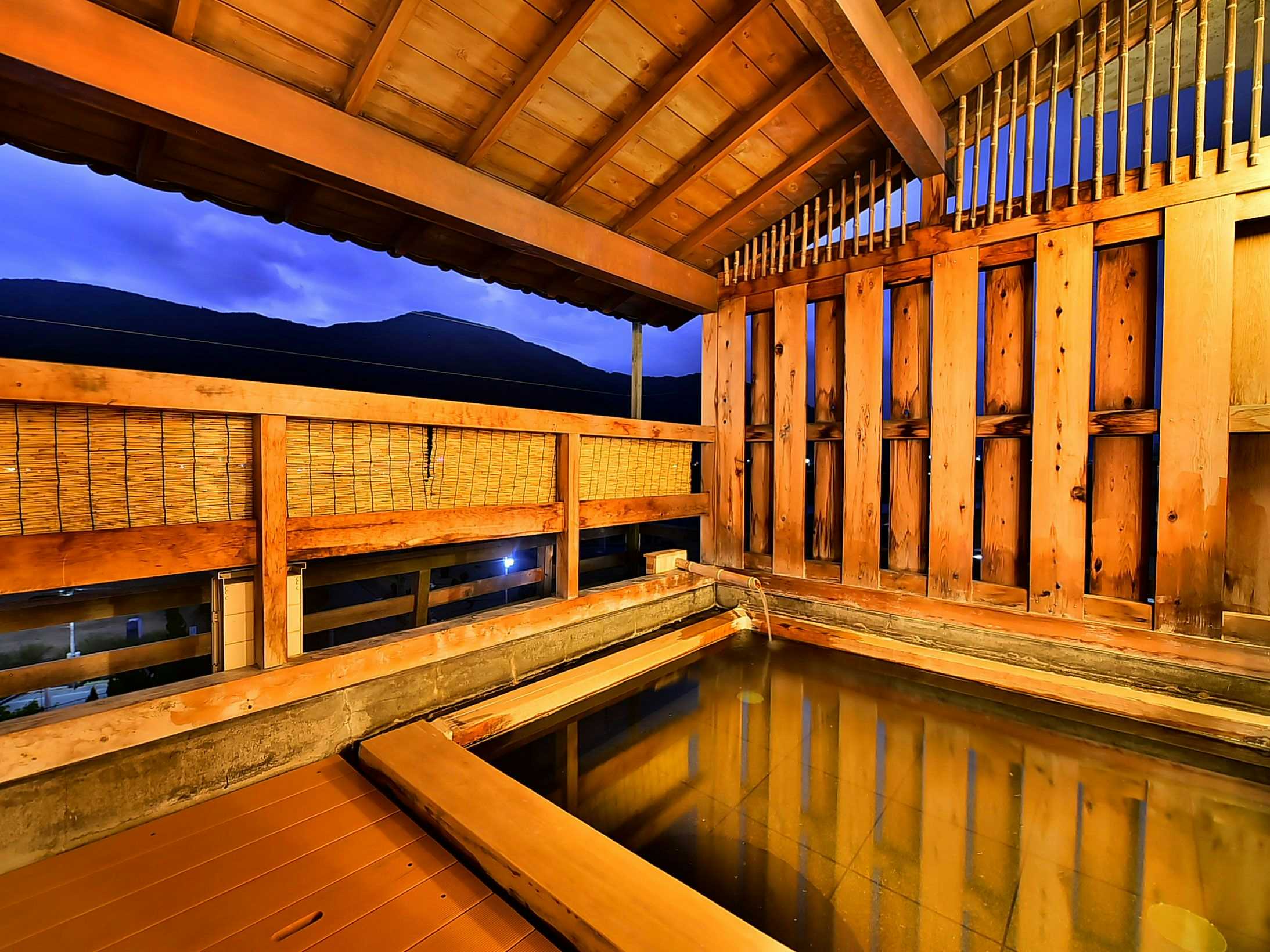 Shinshu Togura Kamiyamada Onsen Tamanoyu with an open-air timber bath overlooking dark mountain slopes.