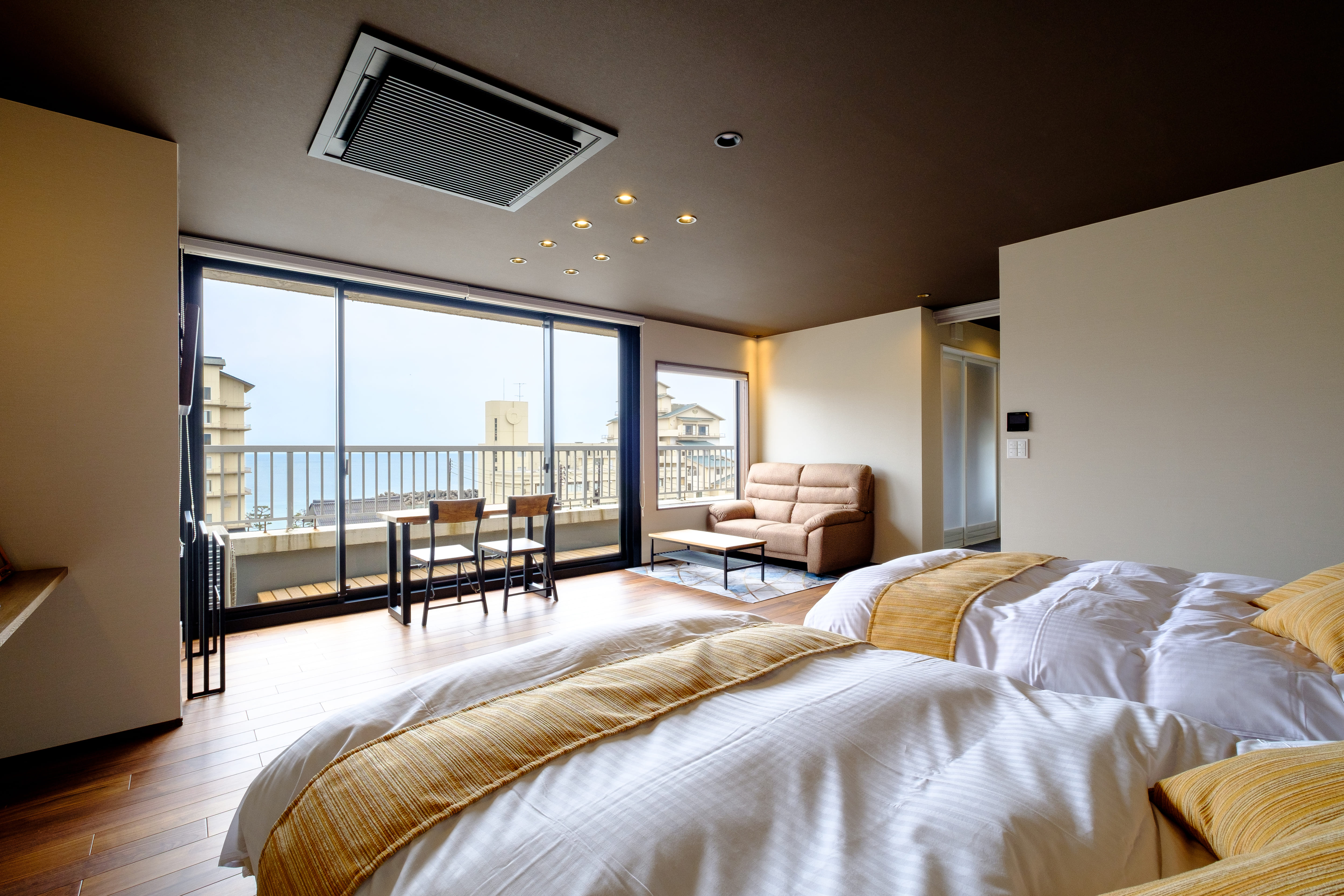 A twin bedroom with a sofa and glass doors to a balcony.