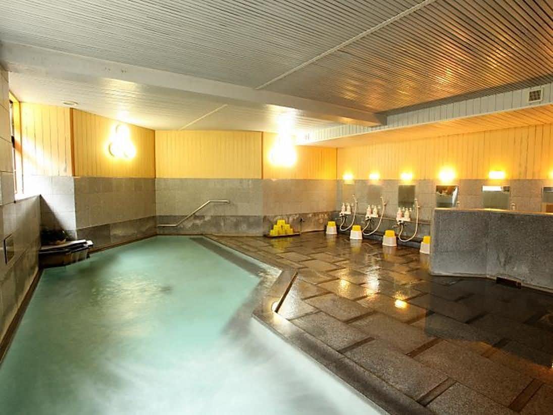 Yumori Takumi-an Yamakawa with a large indoor mineral bath filled with pale blue water.