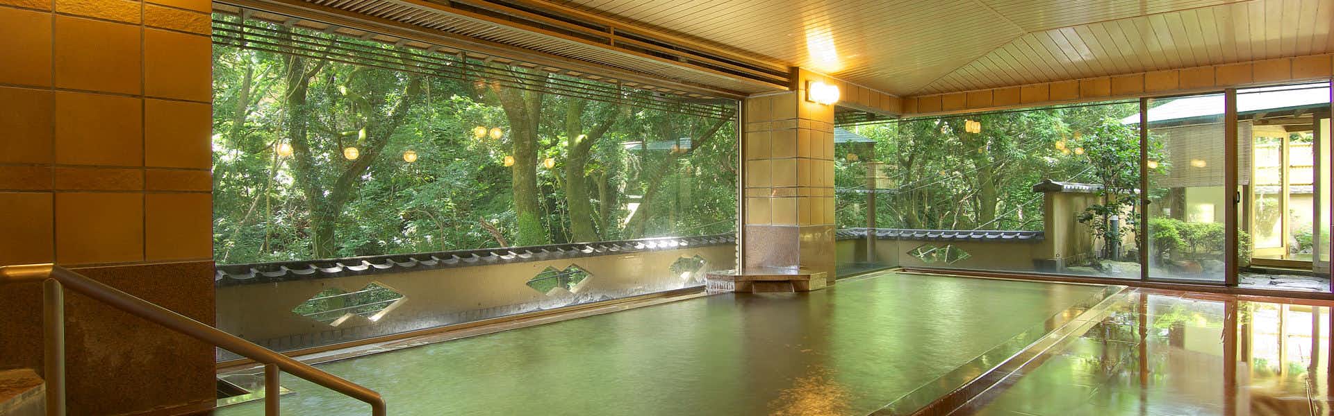 Kawaizuen Isuzu Hotel with a spacious indoor bath overlooking leafy garden trees.