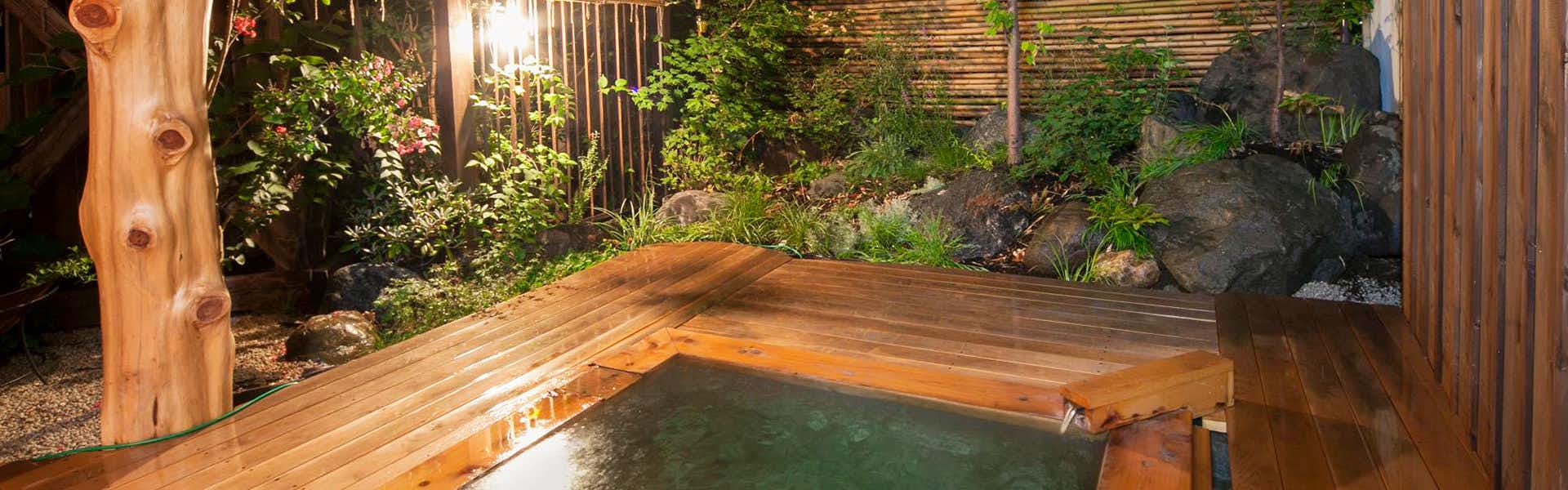 Kamekiyo Ryokan wooden outdoor bath set beside a small rock garden.