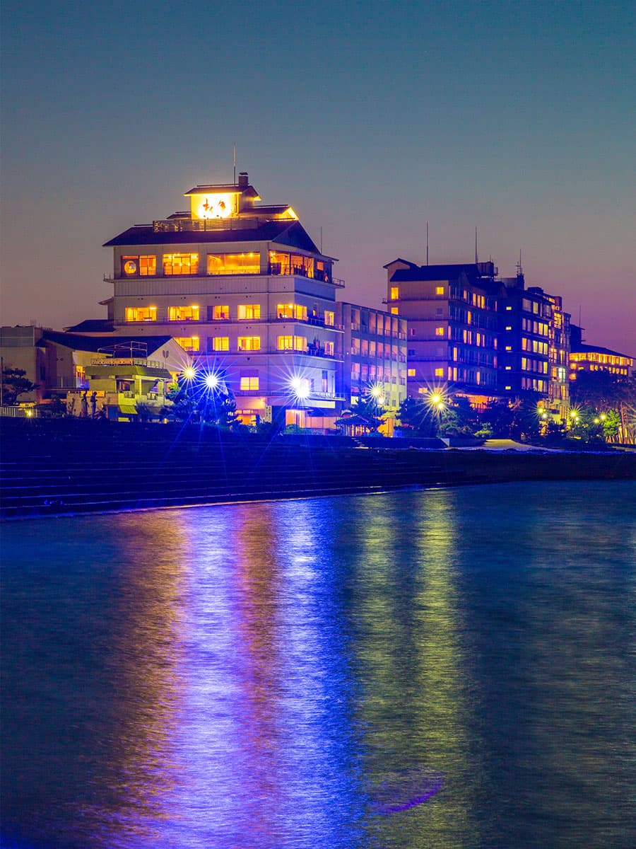 Its illuminated seafront exterior reflected in the evening water.