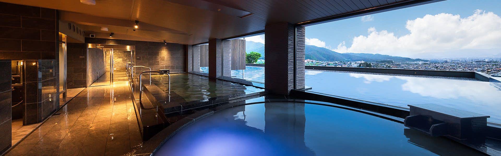 Shinshu Matsumoto Utsukushigahara Onsen Shouhou with an indoor mineral bath overlooking distant city lights.