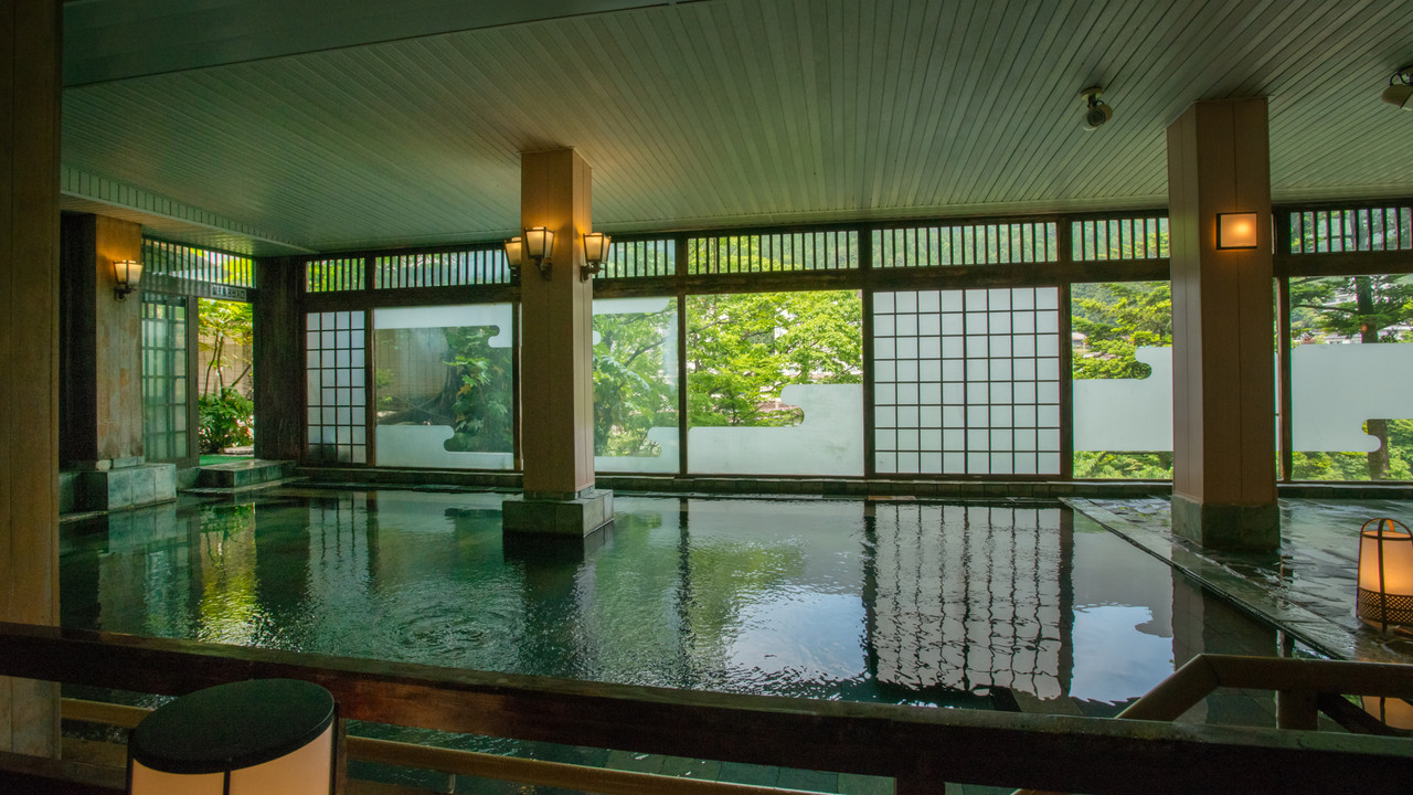 A spacious bath is framed by shoji screens and greenery.