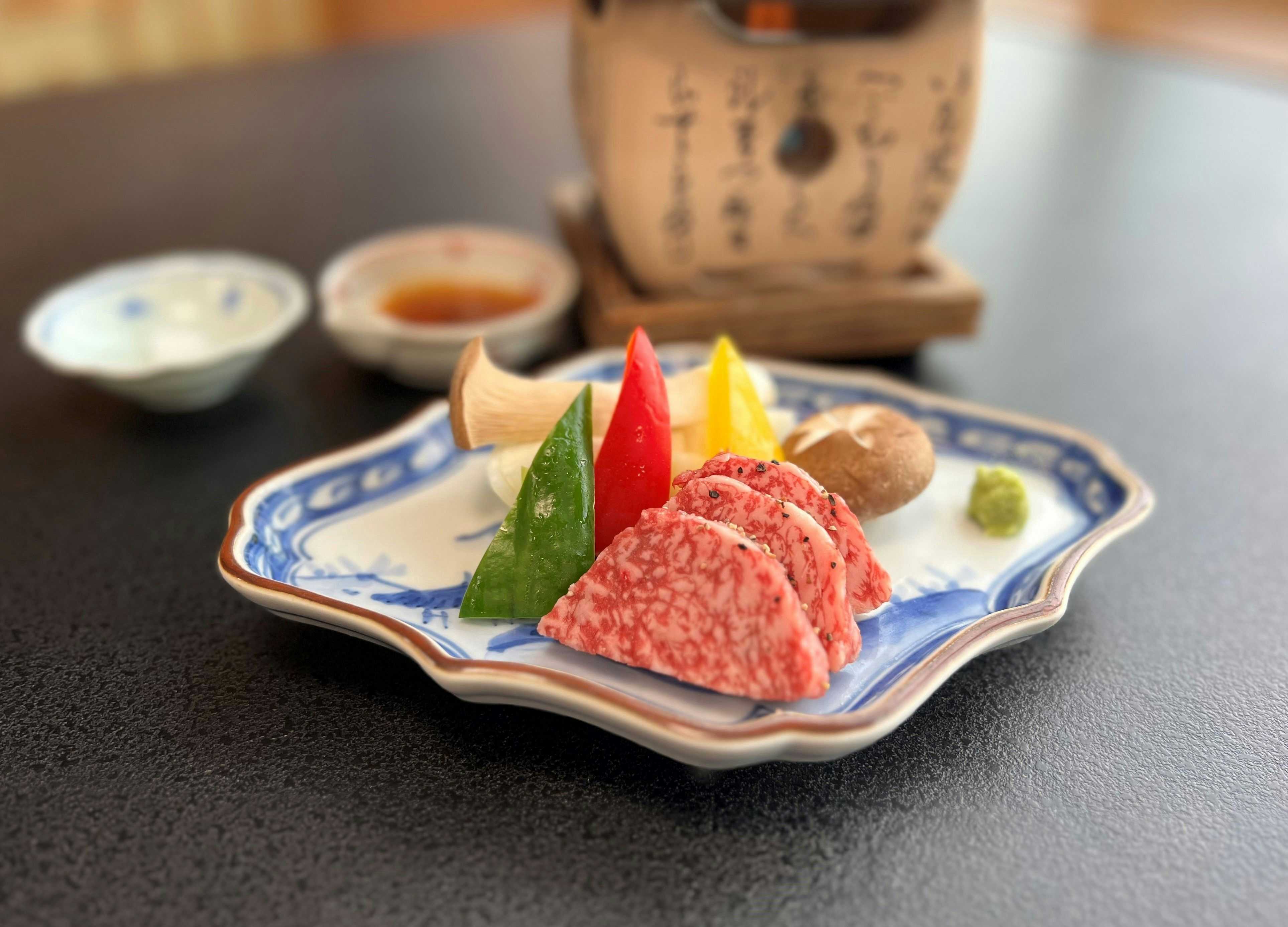 Semi Onsen with marbled beef slices served with wasabi on blue ceramic.