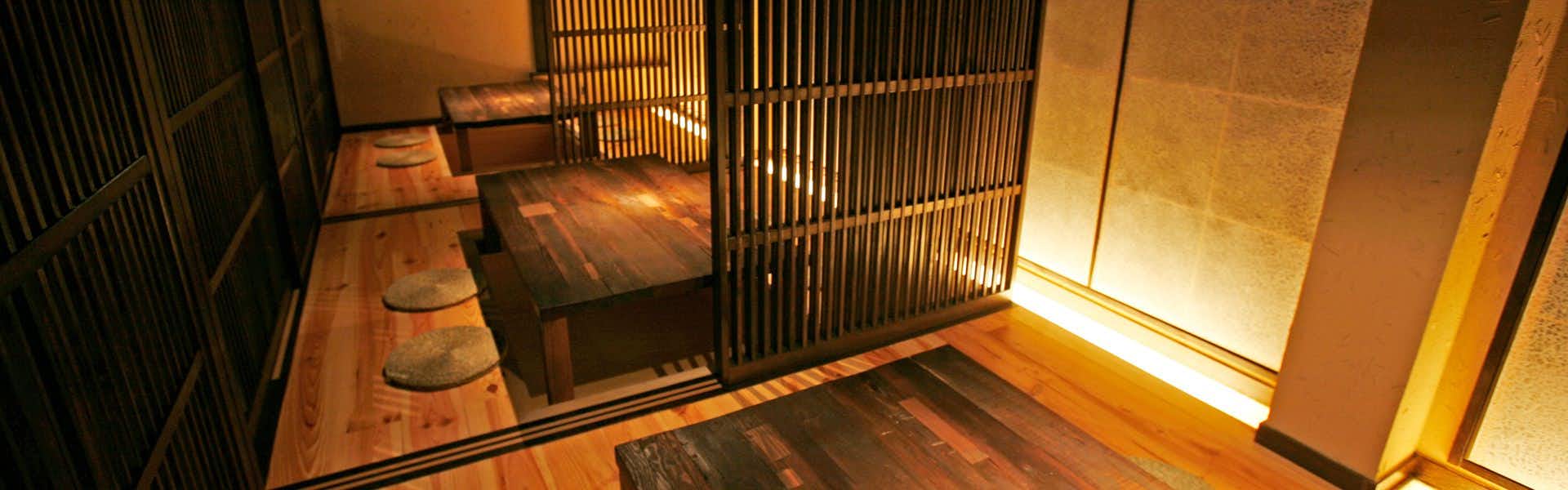 Mamaneyu Masutomi Ryokan with a warmly lit timber corridor lined with dark vertical screens.