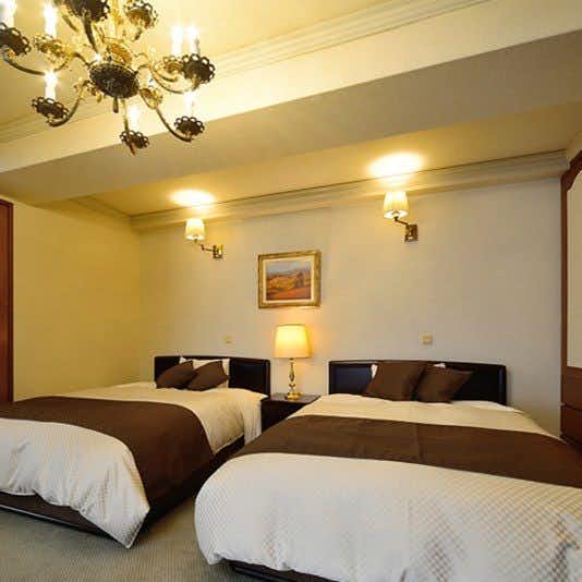 Showa Club with a western twin bedroom beneath a crystal chandelier.