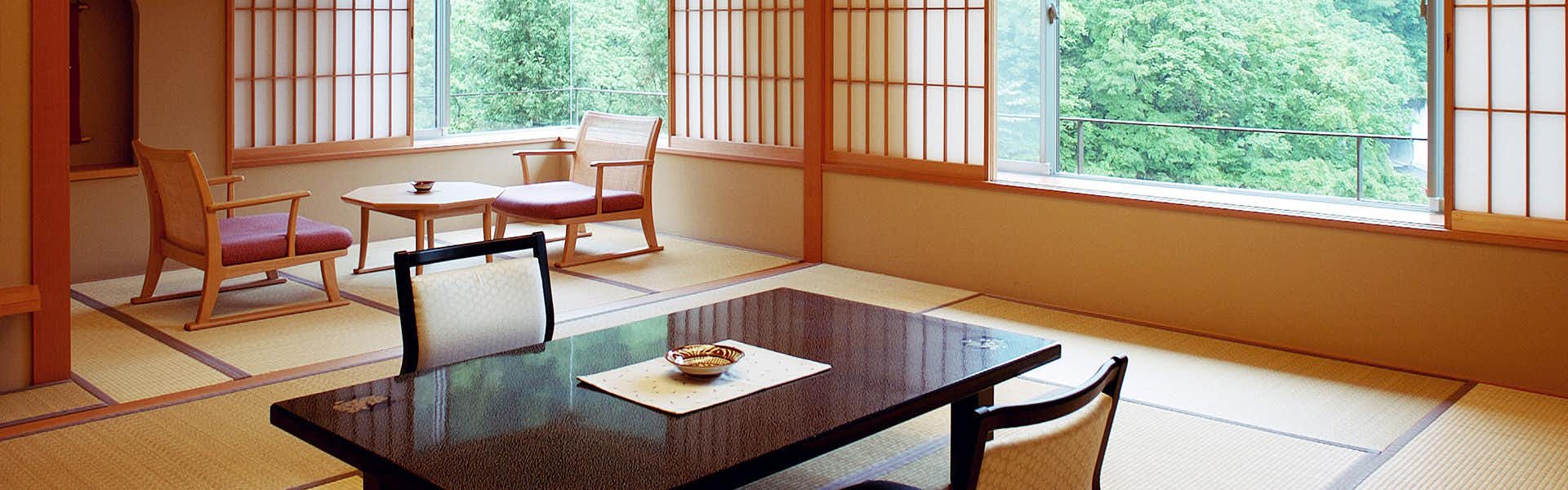 Yomogihira Onsen Izumiya room interior with wooden low table, beige walls, and latticed window shades