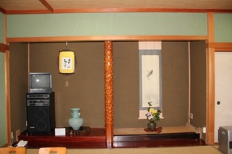 A room alcove with a hanging scroll and ceramic vase.