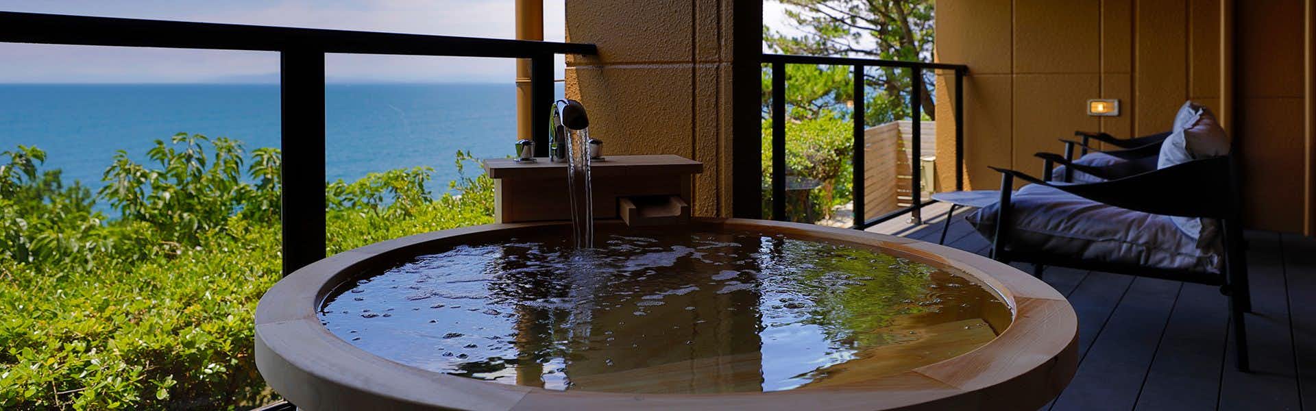 Umi no Hotel Isaba with a circular private bath overlooking trees and the blue sea.