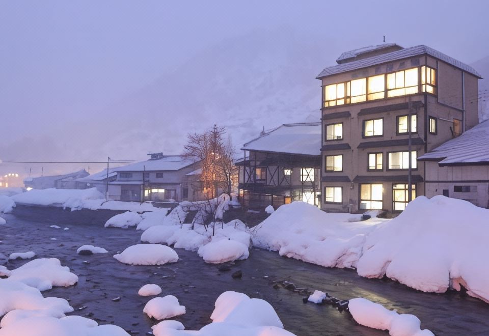 A snow-covered ryokan exterior at dusk.