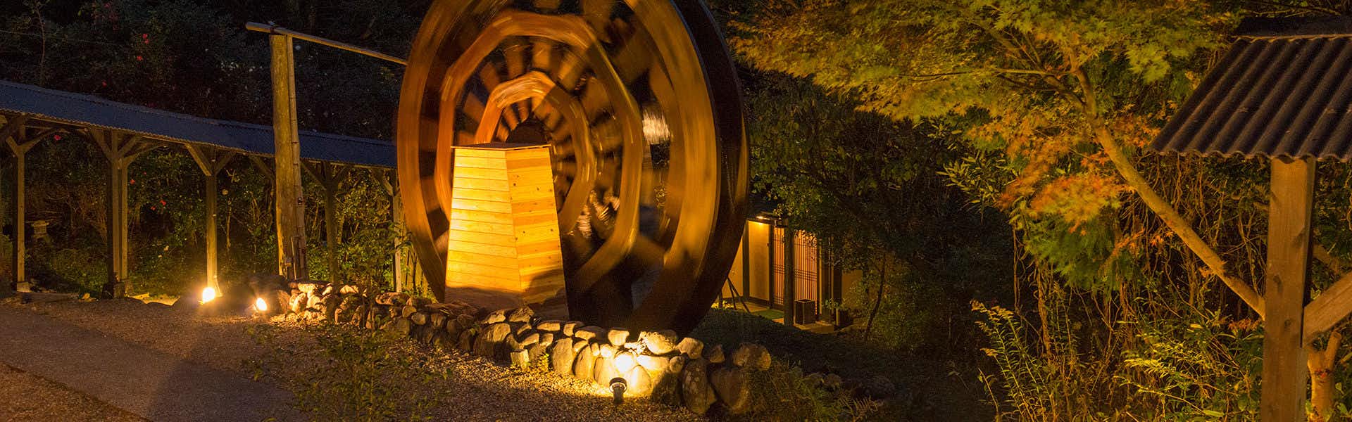 Suisyanoyado syouen with a large wooden water wheel glowing in the night garden.