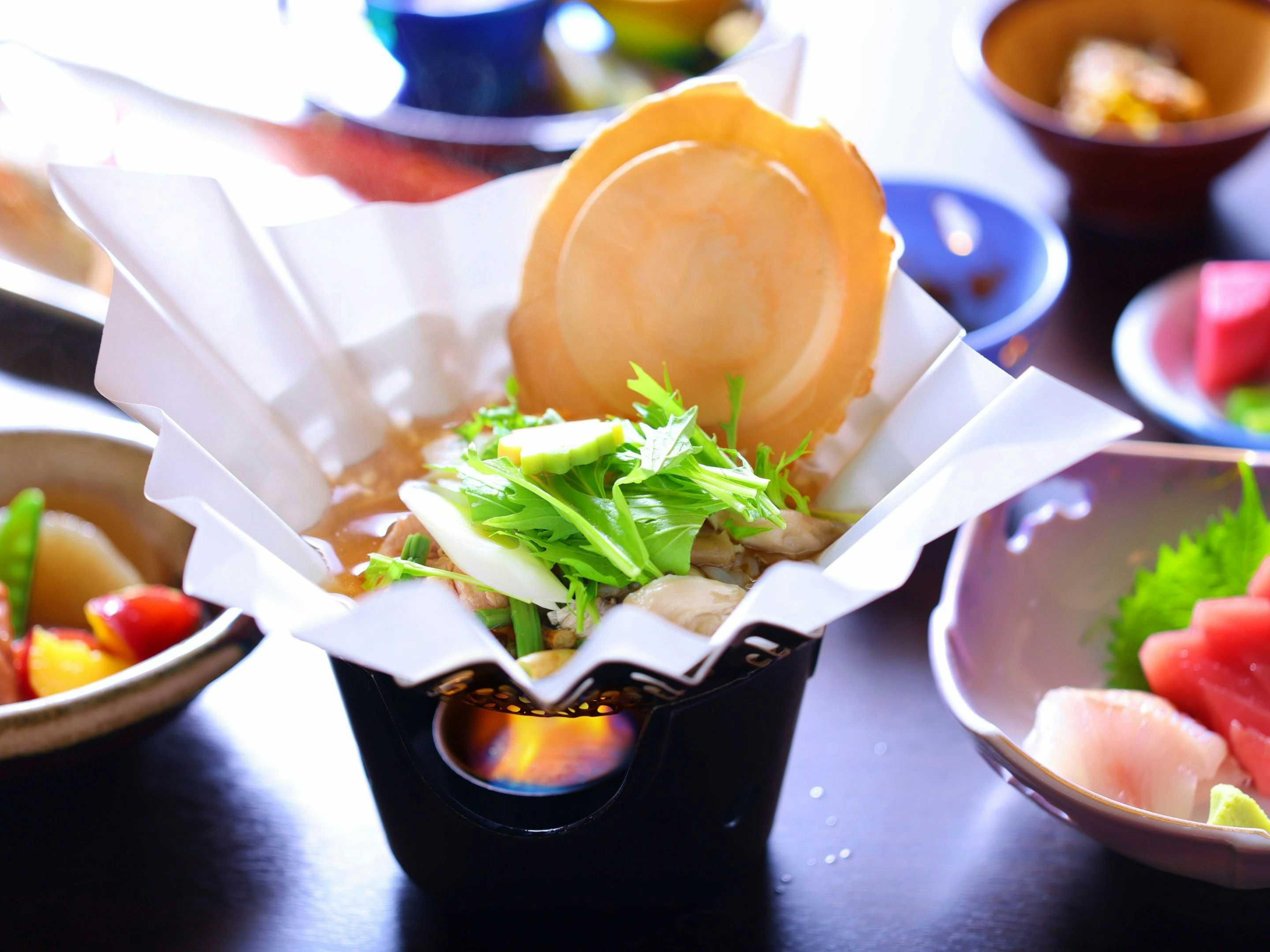 Sukayu Onsen Ryokan with a black bowl, sliced food, green garnish, and surrounding plates
